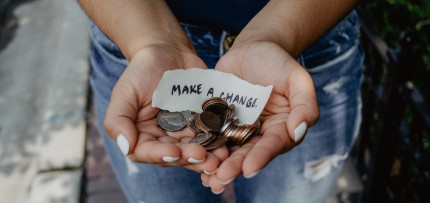 אשה מחזיקה מטבעות בידיים פתוחות, עם פתק ועליו הכיתוב עשו שינוי (צילום: rawpixel / CC0)